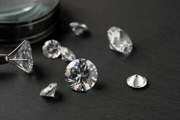 Brilliant cut diamond held by tweezers on black background