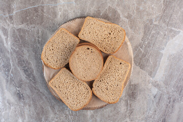 Slices of brown bread on a wooden board on marble background