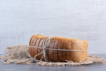 Tied-up block of sliced bread on a piece of cloth on marble background