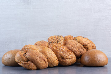 Loaves of baton strucia and bun bread bundled on marble background