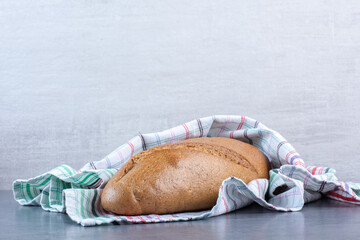 Baton bread wrapping in a towel on marble background