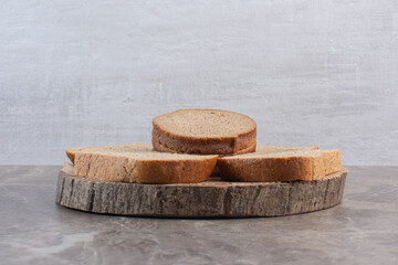 Slices of brown bread on a wooden board on marble background