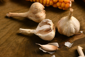 still life of food in a rural style on a dark wood background, corn and garlic, concept of fresh vegetables and healthy food