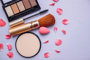 Decorative cosmetics mascara, powder, eye shadow, sponge, brushes on a purple background close-up with an empty space for text, the concept of daytime and evening makeup, self-care, beauty products