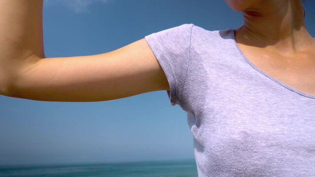 Close-up of woman with hyperhidrosis of sweating. Young with sweat stain on her clothes outside by sea. Healthcare concept. hyperhidrosis sweats under arm, does not feel well with body,