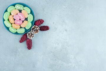 Pine cone arrangement and a platter of marmelades on marble background