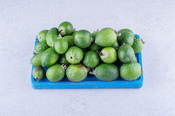 Pile of feijoas on a small platter on marble background
