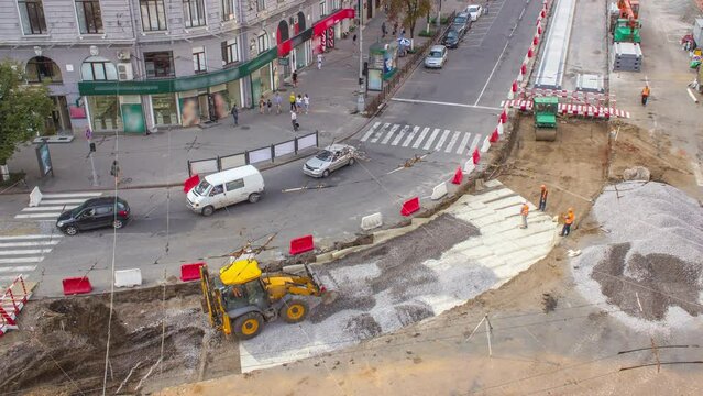 The bulldozer moves and spreads the soil and rubble on the substrate of road timelapse. Aerial top view. Work bulldozer on the reconstruction of a tram tracks. Road under construction.
