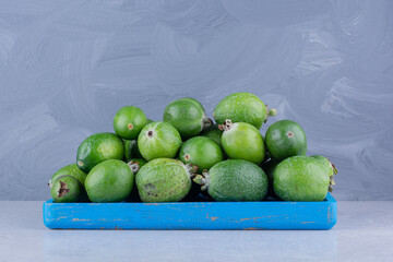 Heap of feijoas on a small platter on marble background