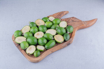 Feijoas bundled up in a wooden tray on marble background