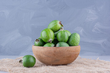 Small bowl of feijoas on a piece of cloth on marble background