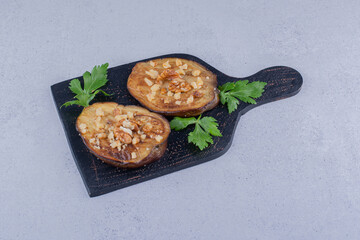 Fried eggplants with parsley leaves on a wooden board on marble background