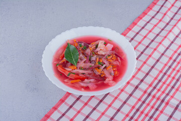Borsch soup with a bay leaf topping on a tablecloth on marble background