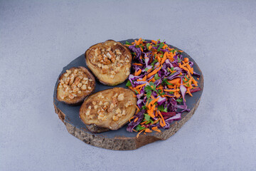 Garlic garnished fried eggplant slices and a portion of salad on marble background
