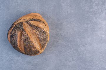 Single loaf of black sesame coated bread on marble background