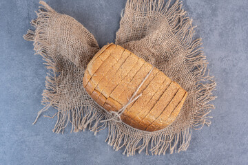 Tied-up block of sliced bread on a piece of cloth on marble background