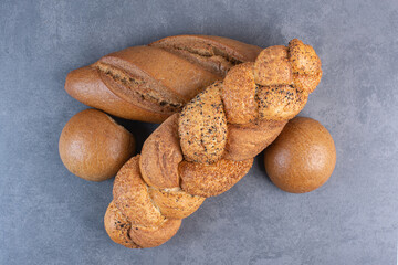 Loaves of baton, strucia and bun bread bundled on marble background