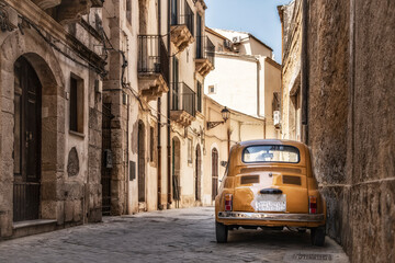 Old yellow Fiat 500 in the city centre of Syracuse in Sicily, Italy - obrazy, fototapety, plakaty