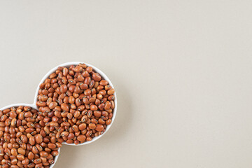 Brown beans in a ceramic cup on concrete background