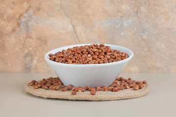 Brown beans in a ceramic cup on concrete background