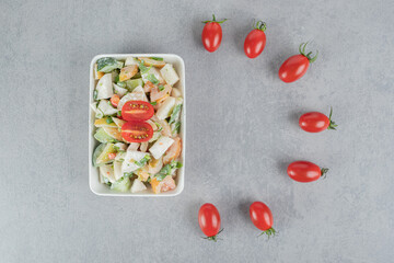 Chopped green tomato salad with herbs and spices on concrete background
