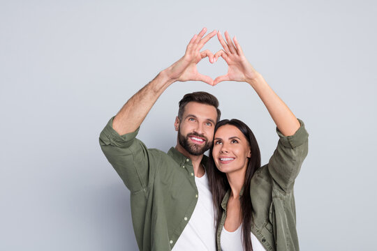Portrait of attractive amorous cheerful couple hugging showing heart symbol amour isolated over grey pastel color background