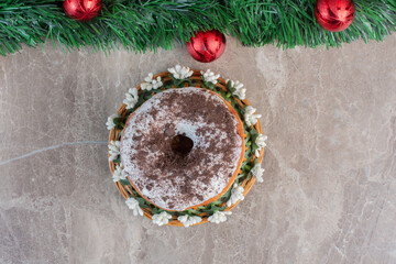 Lined-up christmas wreath next to a single donut on marble background