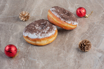 Savory donuts next to a christmas tree decor and a pine cone on marble background