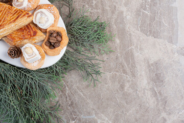 Crisp kyatas, cookies, lokums and pine cones on a platter on marble background