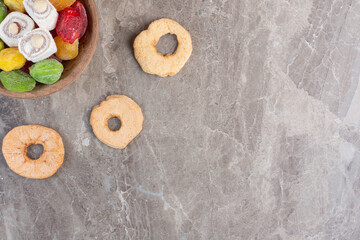 Delicious dried apple slices around a bowl of lokum and marmelades on marble background