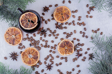 Arrangement of anise seeds, dried orange slices and a cup of tea on white background
