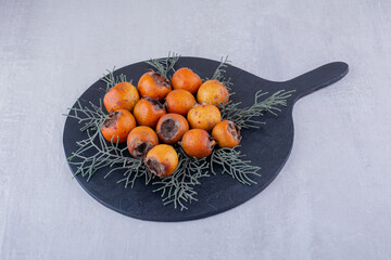 Bundle kakis decorated with pine leaves on a board on white background