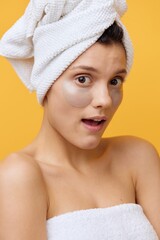  Vertical photo, a woman on an orange background after a shower in a towel on her head and you with patches on her face are surprised