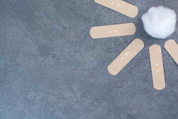 First band aid stickers and cotton ball on marble background