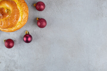 Four christmas tree decorations lined up next to a bun on marble background