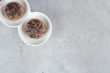 Two chocolate chip cookies on a platter on marble background