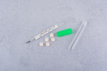 Thermometer and medical pills on marble background