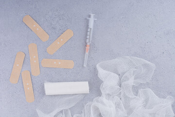 Band aid plaster strips, bandage and syringe on marble surface