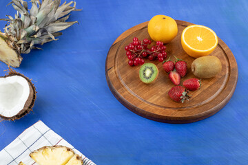 A wooden board with sliced fruits on blue background