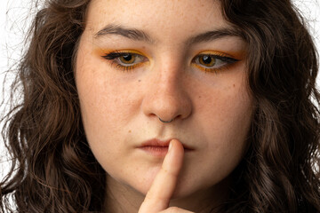 Young woman with finger to mouth as if to say be quiet