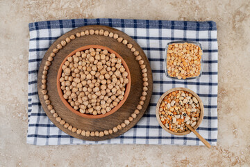 A wooden bowl full of unprepared peas with spices and beans