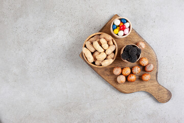 A wooden cutting board with nuts and blackberry