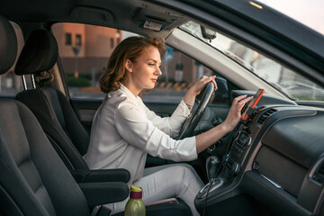 Pensive stylish middle aged business woman driving car using navigation map searching best way. Transportation concept 