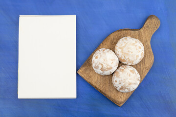 A wooden cutting board with three gingerbread and sheet of paper