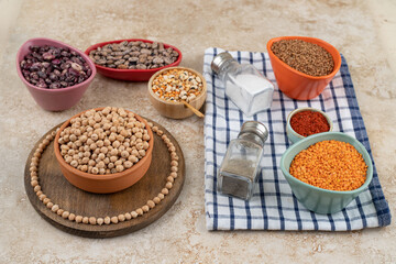 A wooden bowl full of unprepared peas with spices and beans