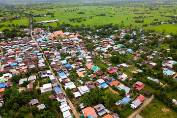 Top view Aerial photo from flying drone over Beautiful green rice field and village from above.The road passes through small villages and leads to green rice fields.OLd house in the northeastern Thai.