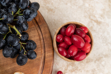 A wooden bowl full of rosehips with grapes