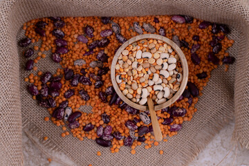 Delicious lentils and beans in wooden bowl on marble background