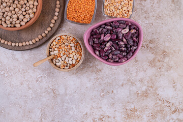 Delicious lentils and beans in plates on marble background