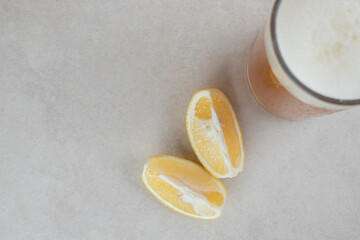 Glass of beer with lemon slices on stone surface